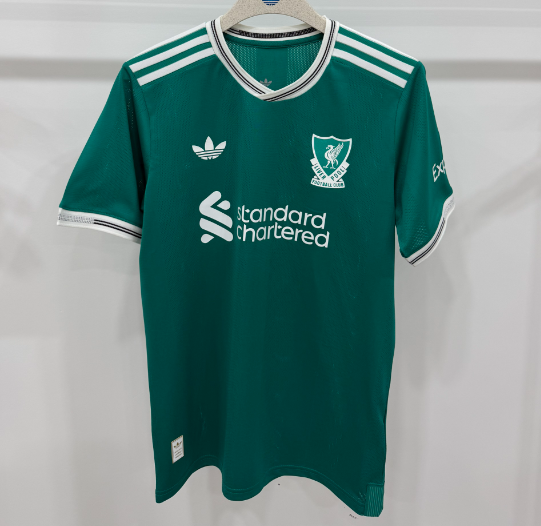 Green sports jersey with Adidas logo on a hanger against a white background